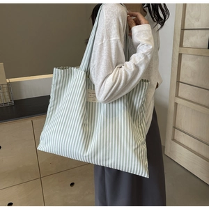 Close-up of green and white vertical striped canvas tote bag with a fabric patch detail
