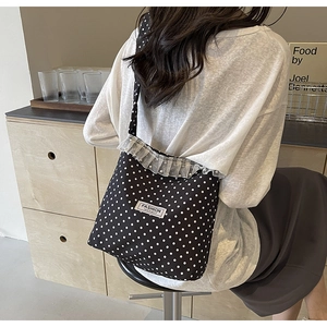 Close-up of black polka dot canvas bag featuring lace trim and a fashion woven label