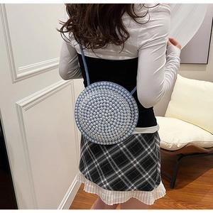 Dettaglio della borsa a tracolla blu circolare con perle bianche e sottile cinturino blu