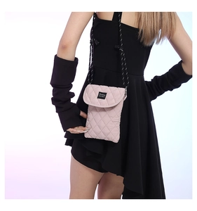 Detail view of pink quilted fabric phone bag with Fashion label and woven strap