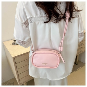 Close-up of pink PU leather crossbody bag with woven knot strap and gold lettering detail