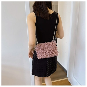 Detail of pink ruffled fabric crossbody bag featuring a delicate gold chain shoulder strap
