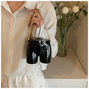 Close-up of creative black mirror-finish mini bag with golden metal snake chain strap