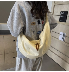 Detailed texture of cream-colored canvas crossbody bag with brown leather zipper pullers