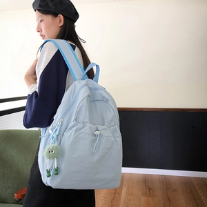 Dettaglio dello zaino in nylon azzurro con tasca a coulisse e ciondolo in peluche verde
