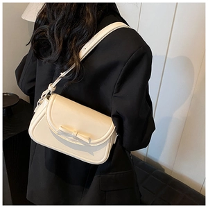 Borsa a tracolla in PU crema con fiocco 3D indossata su un blazer nero chic
