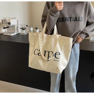 Close-up of cream canvas tote bag with carpe dienn print in a cozy cafe setting