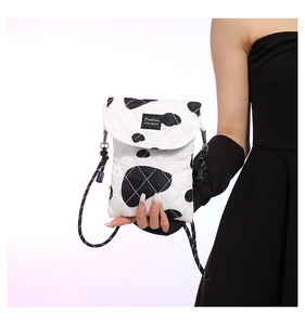 Detail of a quilted cow print crossbody bag with fashion label and braided strap