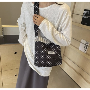 Detail of black polka dot canvas bag with white lace trim and adjustable shoulder strap