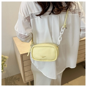 Detail of a lemon yellow PU crossbody bag featuring thick white chain links on the strap