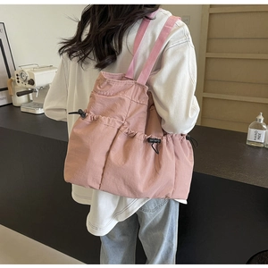 Detailansicht der pinkfarbenen Nylon-Tragetasche mit Kordelzugtaschen und Schultergurten