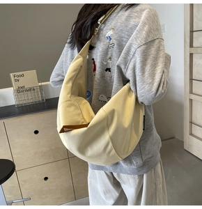 Detail view of beige canvas crescent crossbody bag with wide strap on model back