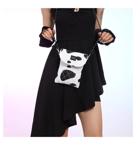 Detail shot of white quilted fabric crossbody bag with black polka dots and Fashion label