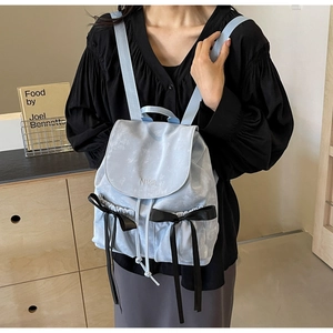 Close-up of light blue marble pattern backpack with black ribbon bows and NiKa embroidery