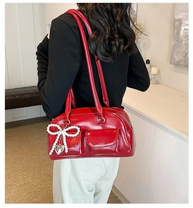 Detailed view of red glossy PU shoulder bag with pearl bow and heart charm