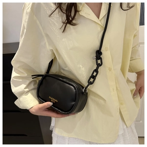 Close-up of black matte PU leather crossbody bag with knot detail and gold branding