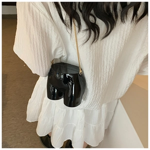 Detail of unique creative art hip shaped crossbody bag with a sleek black glossy finish