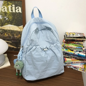 Dettaglio dello zaino in nylon azzurro con coulisse bianca e ciondolo in peluche verde