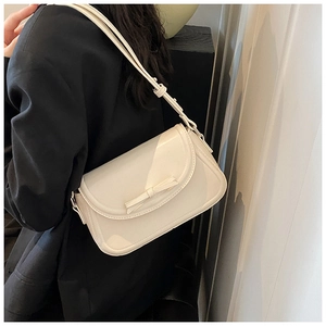 Dettaglio della borsa a tracolla in pelle PU bianca con decorazione a fiocco minimalista sulla patta