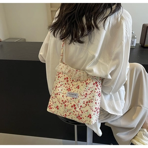 Detail of floral canvas crossbody bag with delicate lace edge and pearl accents