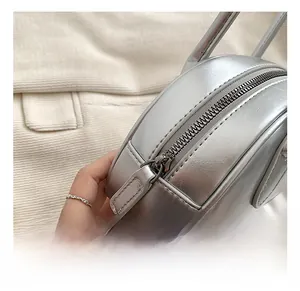 Close-up of silver PU leather round bag showing metallic texture and smooth zipper detail