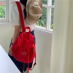 Minimalist red nylon backpack for women featuring flap cover and silver metal hardware