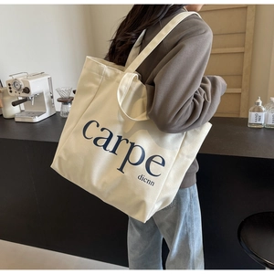 Detail of a cream canvas tote bag with twin handles shown in a modern cafe setting