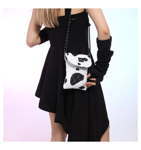 Close-up of black and white cow print quilted fabric mobile phone crossbody bag