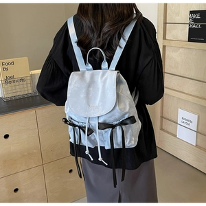 Detail of light blue PU leather backpack featuring black bows and Nilka embroidery