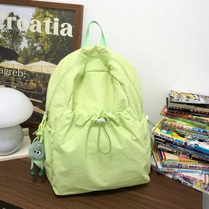 Dettaglio dello zaino in nylon verde neon con tasca anteriore a coulisse e ciondolo