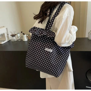 Detailed close-up of large polka dot tote bag with ruffle edge and woven brand label