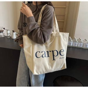 Detail of a large beige canvas tote bag with carpe dienn print on modern cafe background