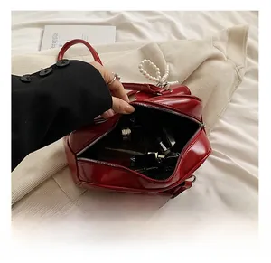 Internal view of red patent leather shoulder bag showing large capacity and pearl zipper