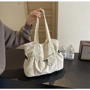 Detailansicht einer cremefarbenen Utility-Tasche mit Taschen und Kordelzug-Details