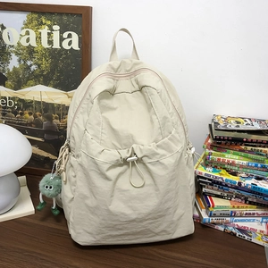 Dettaglio dello zaino in nylon bianco sporco con tasca a coulisse e ciondolo di peluche