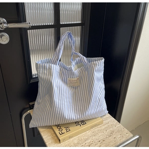 Minimalist blue and white striped canvas tote bag on an artistic marble table setting