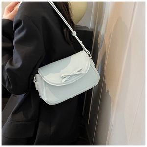 Borsa a tracolla in pelle PU celeste con fiocco decorativo sulla patta, indossata da modella