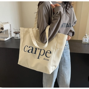 Close-up of a large beige canvas tote bag with carpe dicnn print and double handles