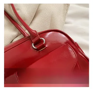 Detail view of glossy dark red PU shoulder bag with silver metal ring and stitch texture
