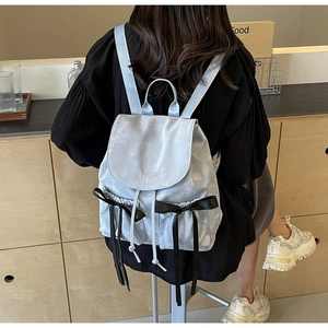 Detail of light blue PU backpack featuring silk bows and embroidered logo on the flap