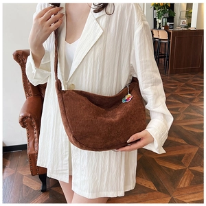 Detailed close-up of brown corduroy crescent bag texture with a cute bear charm