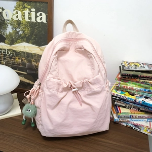 Dettaglio dello zaino in nylon rosa con tasca a coulisse e ciondolo a pallina di peluche