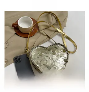 Detail view of heart-shaped sequin crossbody bag with smartphone for size reference