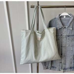 Green and white striped canvas tote bag with central text label and long handles
