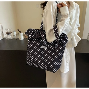 Close-up of black and white polka dot canvas tote bag featuring ruffled edge details