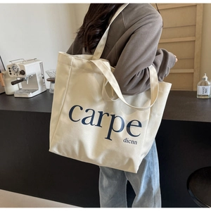 Detailed texture of off-white canvas tote bag with carpe dicnn lettering in a cafe