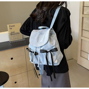 Detail of light blue PU leather backpack featuring black silk bows and marble texture