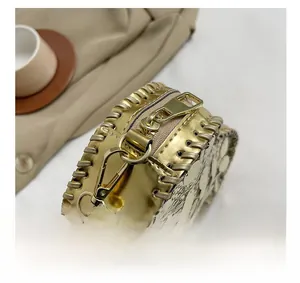 Close-up of golden metallic mirror leather bag featuring woven edges and premium metal zipper