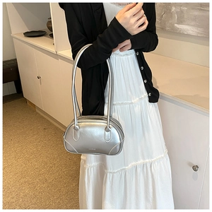 Detail shot of a silver metallic PU leather handbag worn over the shoulder by a model