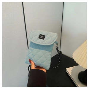 Light blue quilted crossbody bag with rope strap and fashion patch on fabric
